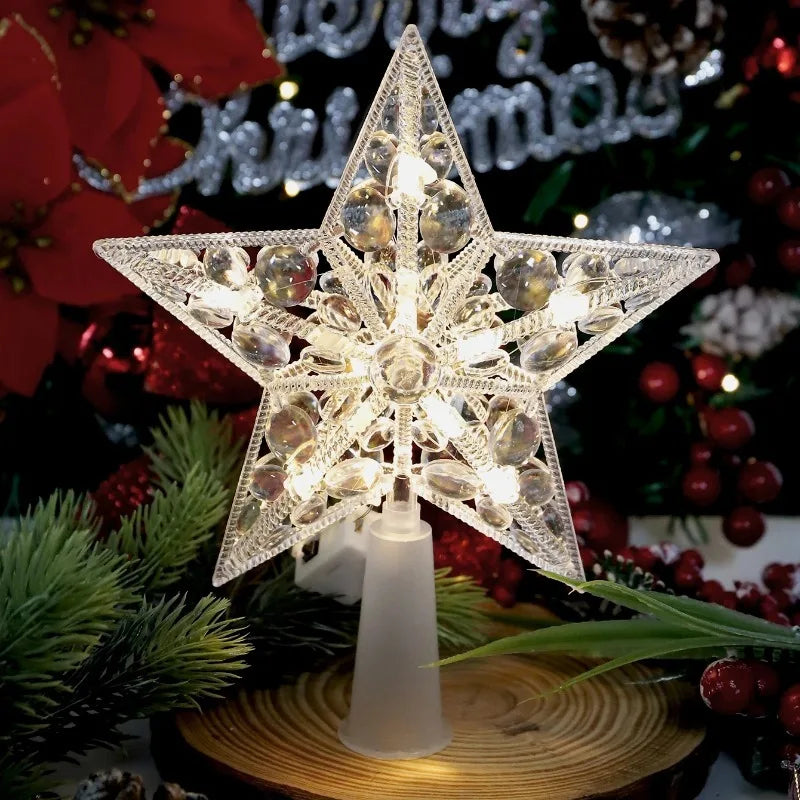 Decorative star-shaped Christmas tree topper with lights on a wooden base, surrounded by festive decorations.