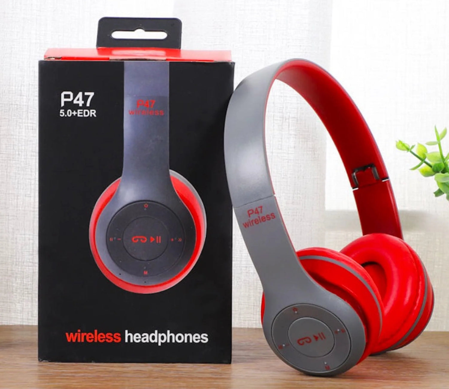 Red and gray wireless headphones with P47 branding next to their packaging on a wooden surface.