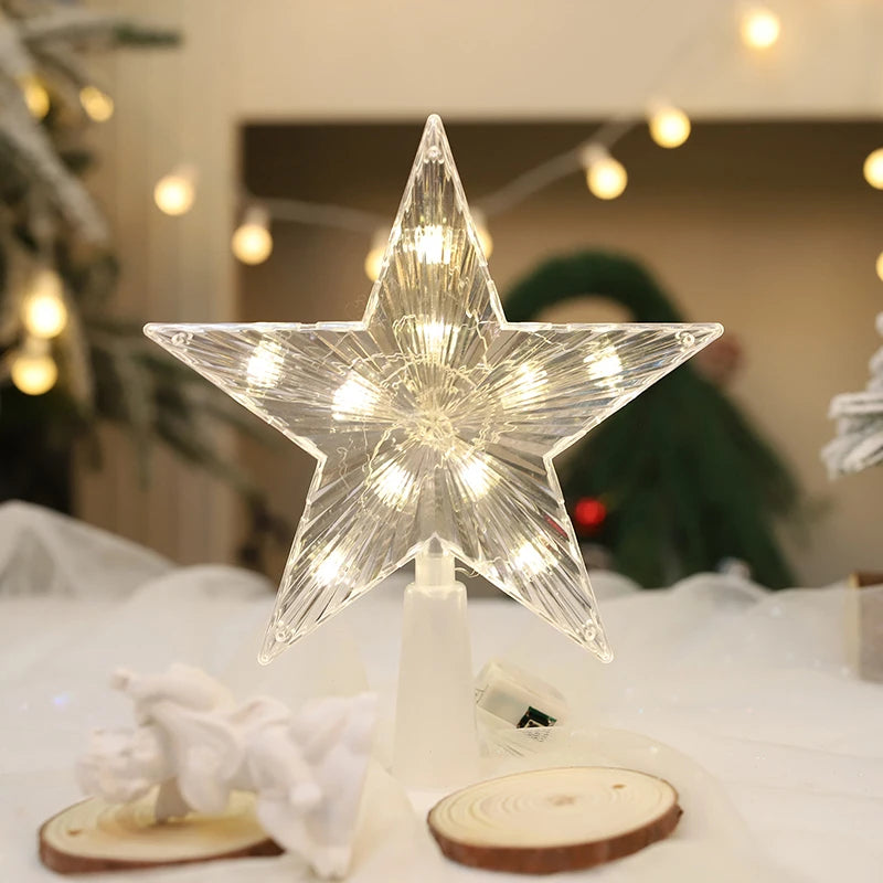 Decorative star-shaped lamp with string lights on a wooden base, blurred Christmas tree in the background